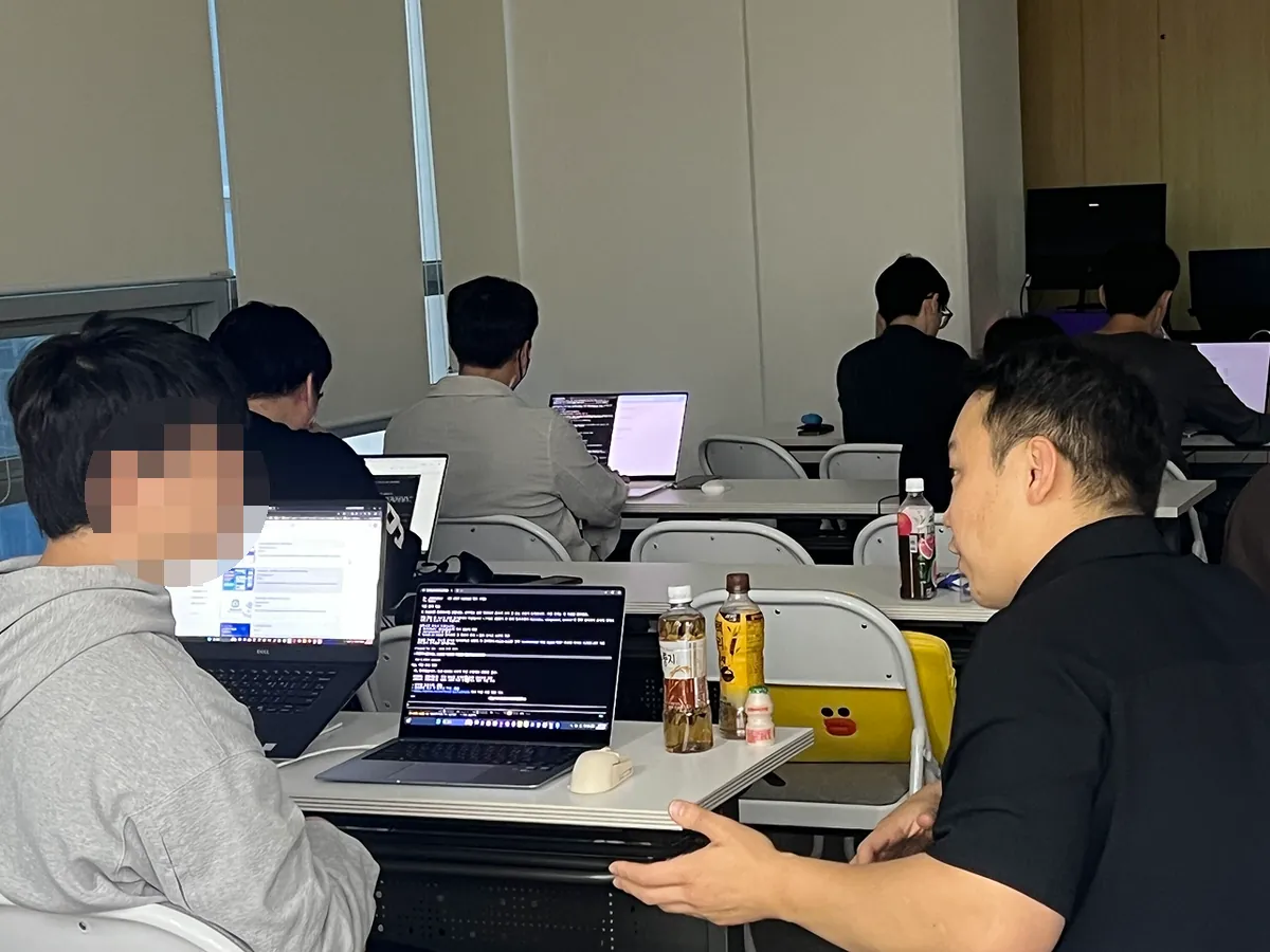 교육 현장: 수강생 옆에 앉아 노트북 화면을 함께 보는 모습